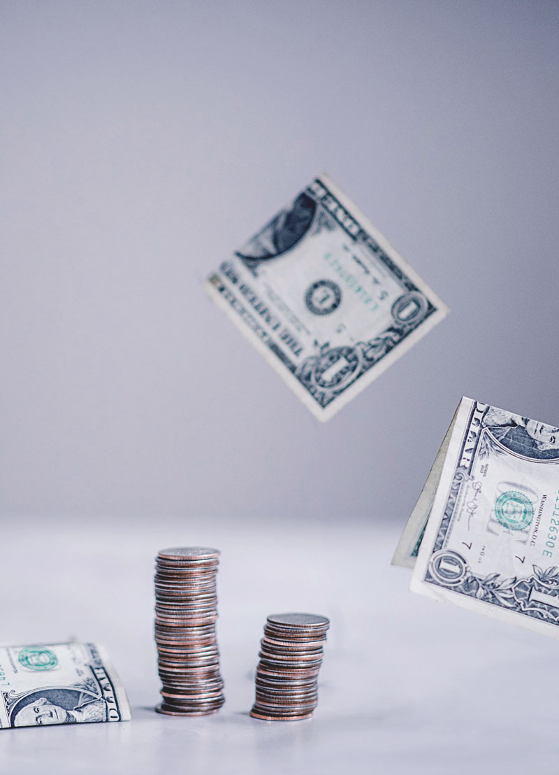 dollar bills falling next to a stack of coins